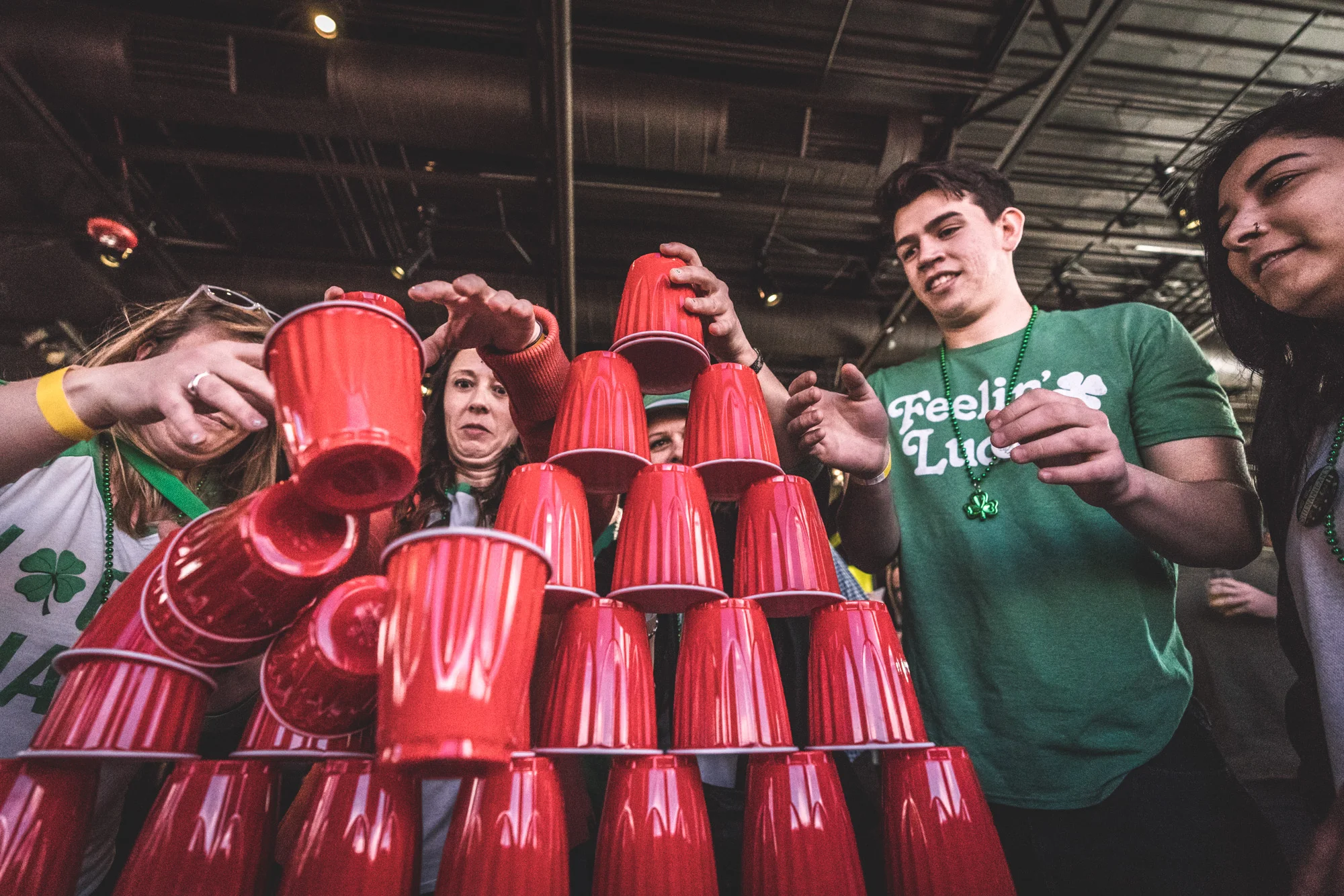 Color photo of a group of people attempting to stack red solo cups at the ASC Shamrock Stumble pub crawl fundraiser for Saint Patrick's Day in Littleton, CO.