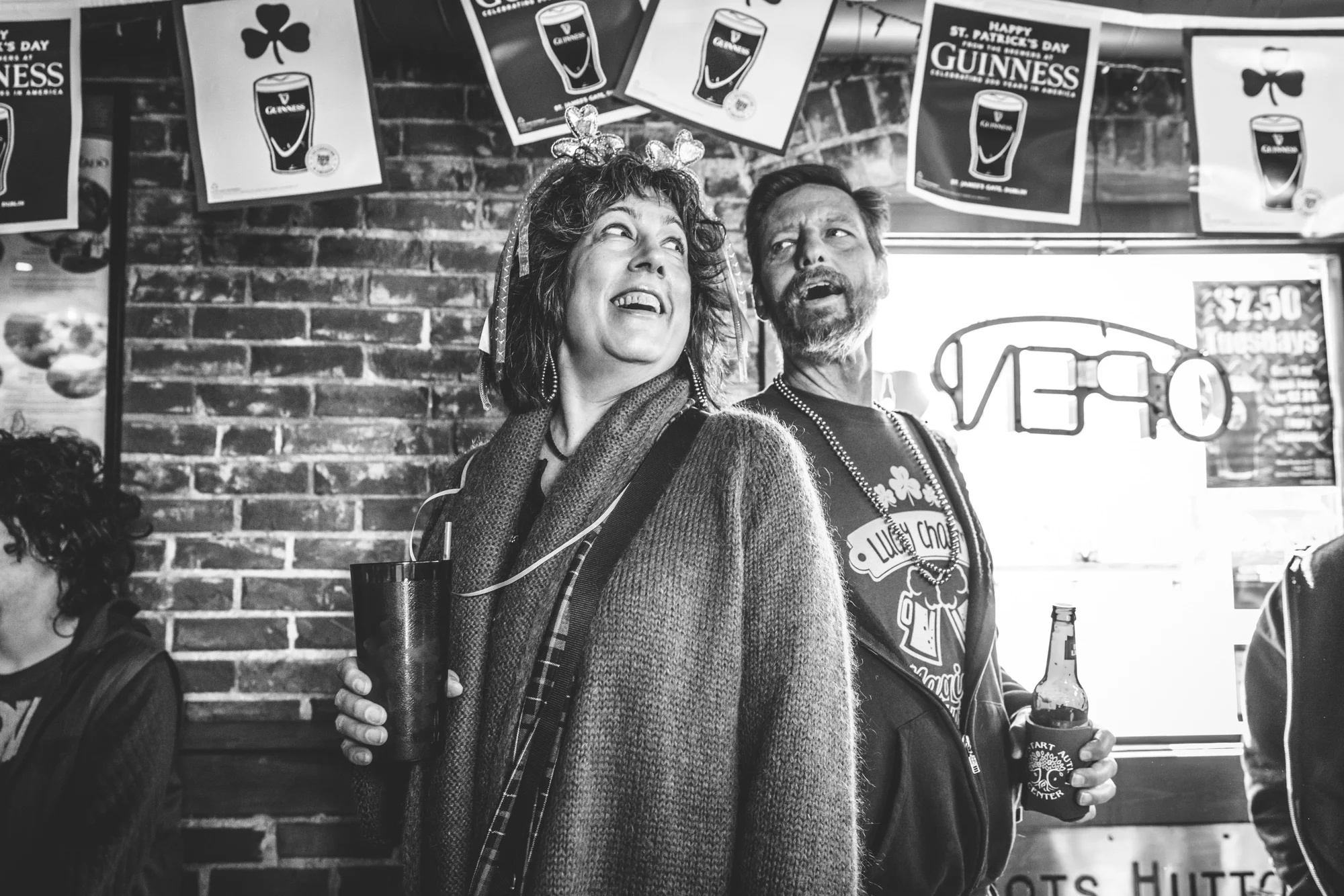 Black and white photo of a tall man and woman standing back to back to compare heights. Taken at Ned Kelly's Irish Pub during the ASC Shamrock Stumble in downtown Littleton, Colorado.