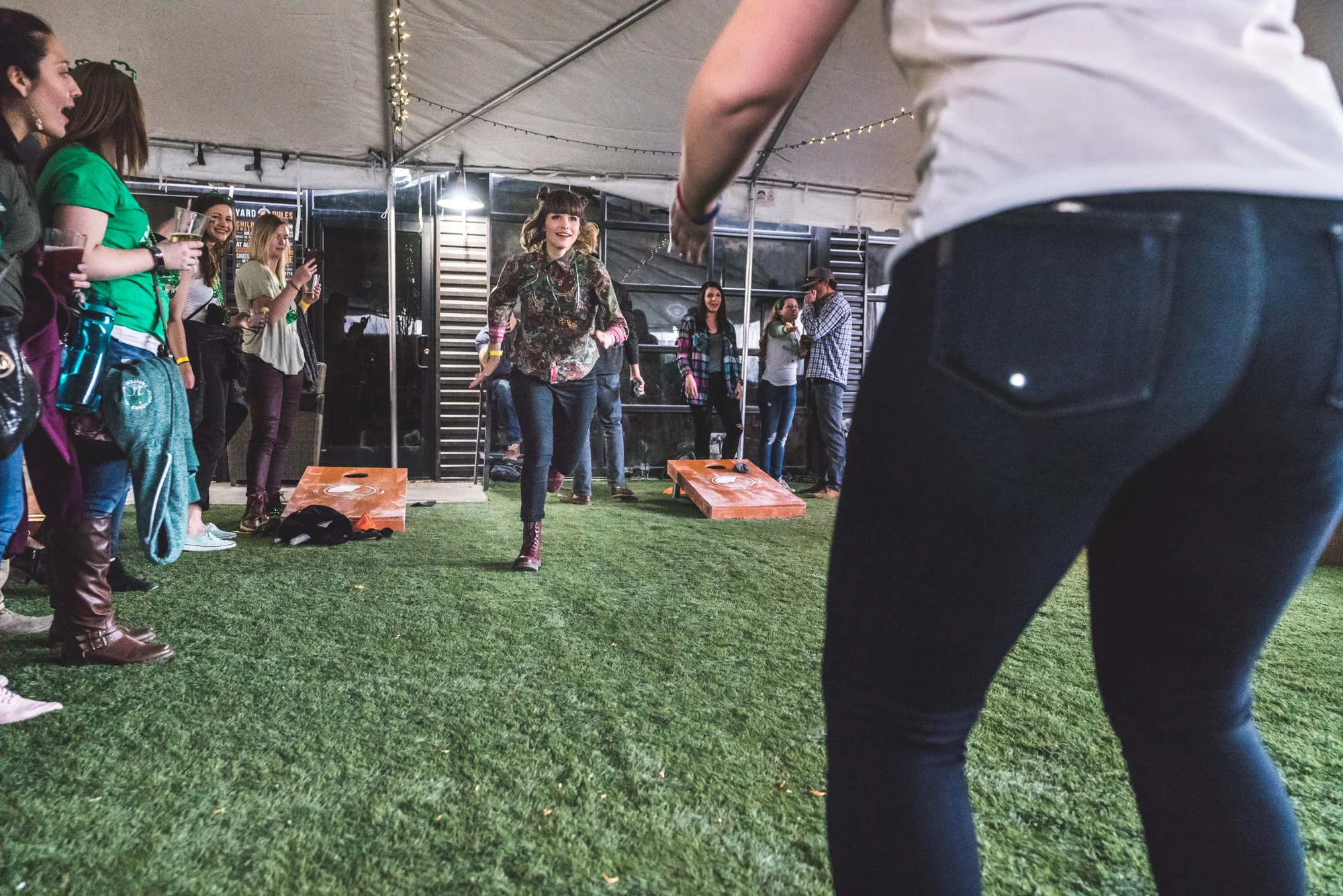Color photo of a woman running toward another woman in a tent outside of the ViewHouse Littleton during the ASC Shamrock Stumble photography session