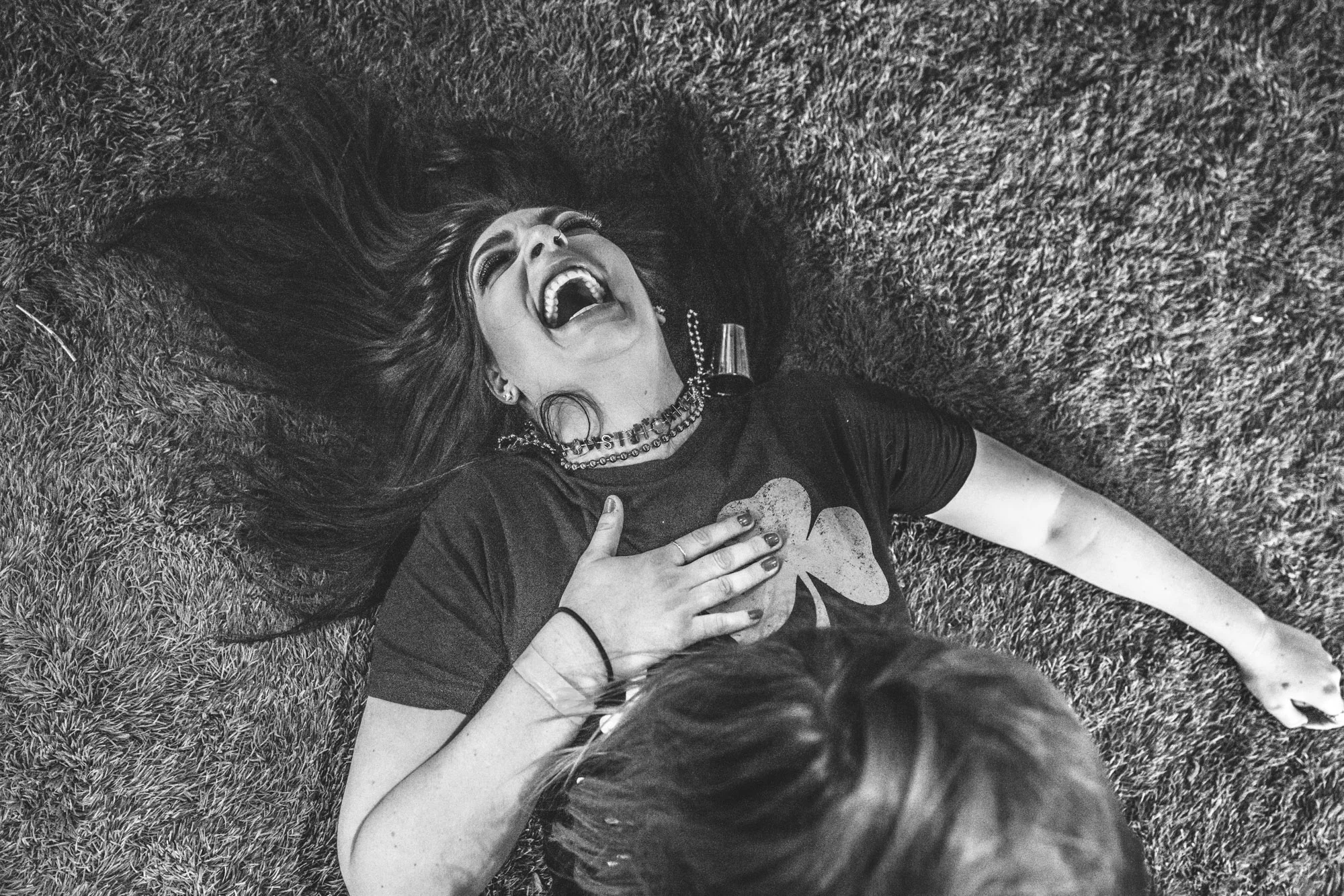 Black and white photo of a young woman lying on the ground laughing hysterically during a dance party at the Autism Society of Colorado Shamrock Stumble fundraiser.