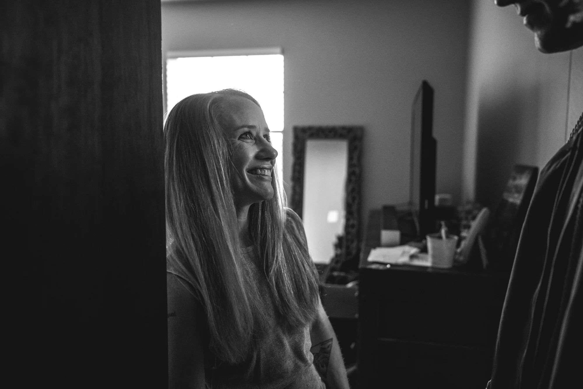 Black and white photo of a mother looking up at her son for the first time in his high school graduation cap and gown. Taken in Denver, CO.