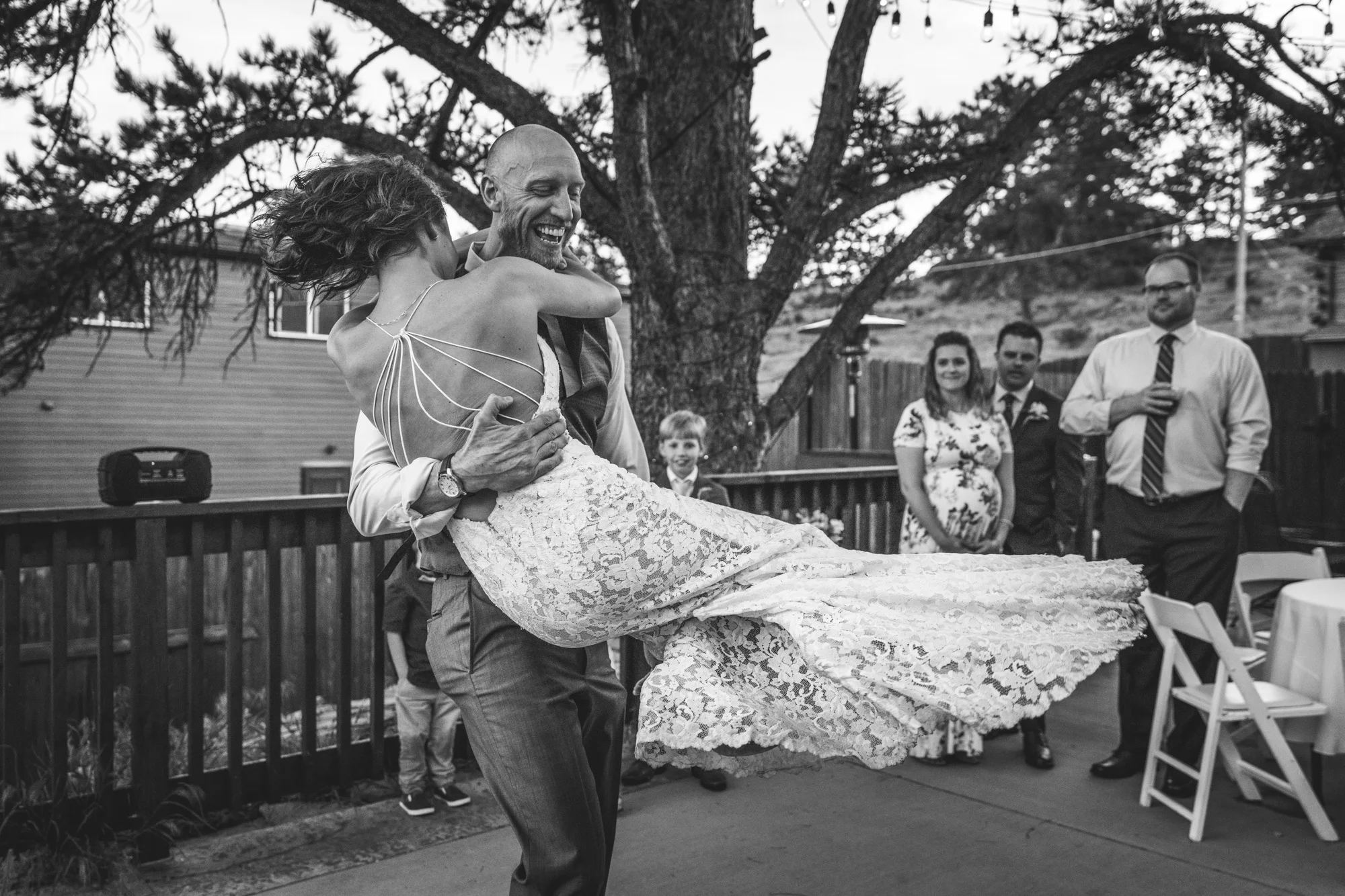 Black and white image of a groom picking up and twirling around his bride on the dance floor at their reception at the Bristlecone Inn in Estes Park, CO.