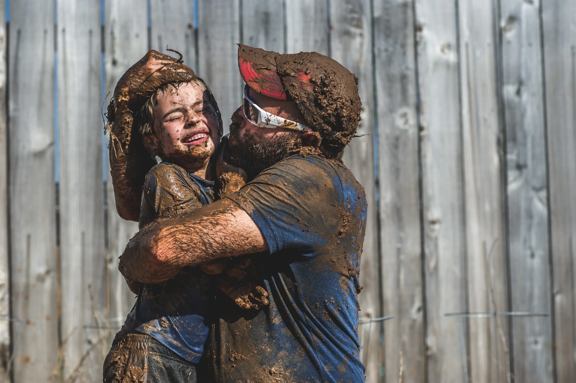 Dad-tries-to-kiss-young-son-while-both-are-covered-in-mud.jpg