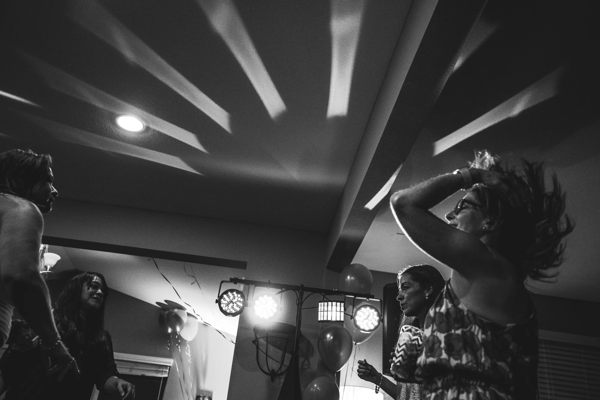 Black and white event photo of a woman flipping her hair back as she dances with the dynamic lights on the ceiling reflecting the movement of the hair