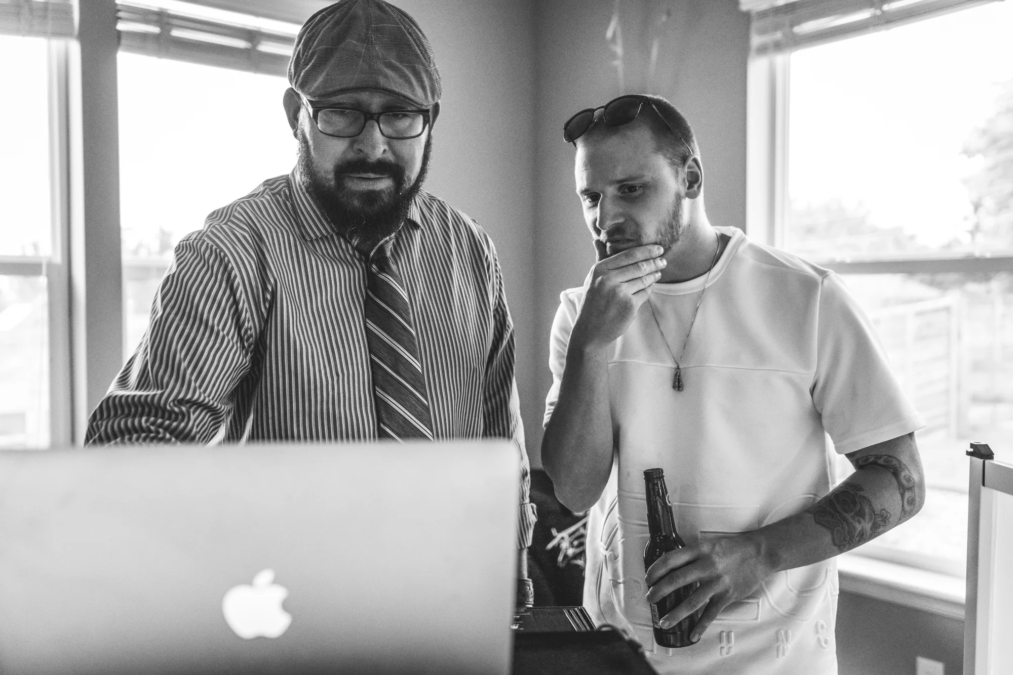 Black and white photo of a man and a DJ looking at a computer, trying to choose the next song
