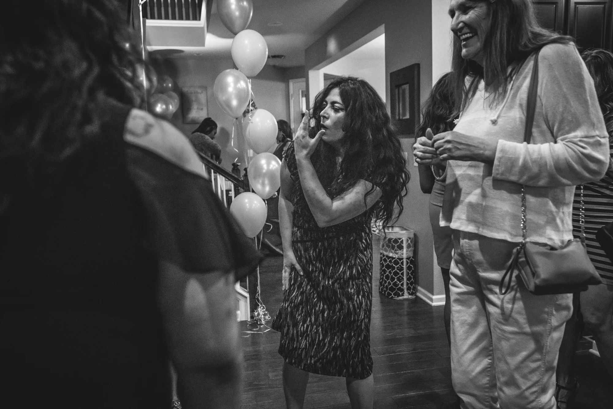 Black and white image of a woman doing a funny dance move at a birthday party at a home in Denver