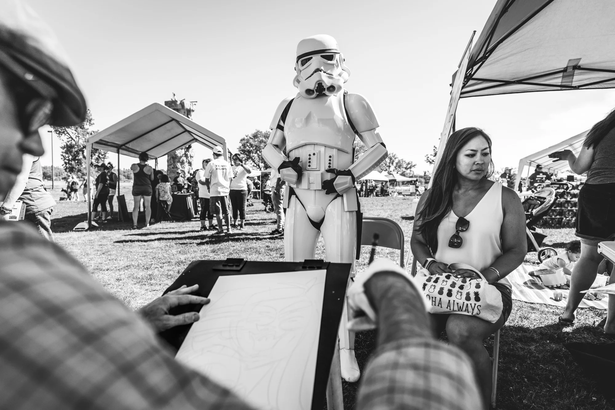 Black and white image at an outdoor charity event of a storm trooper getting drawn by a caricaturist