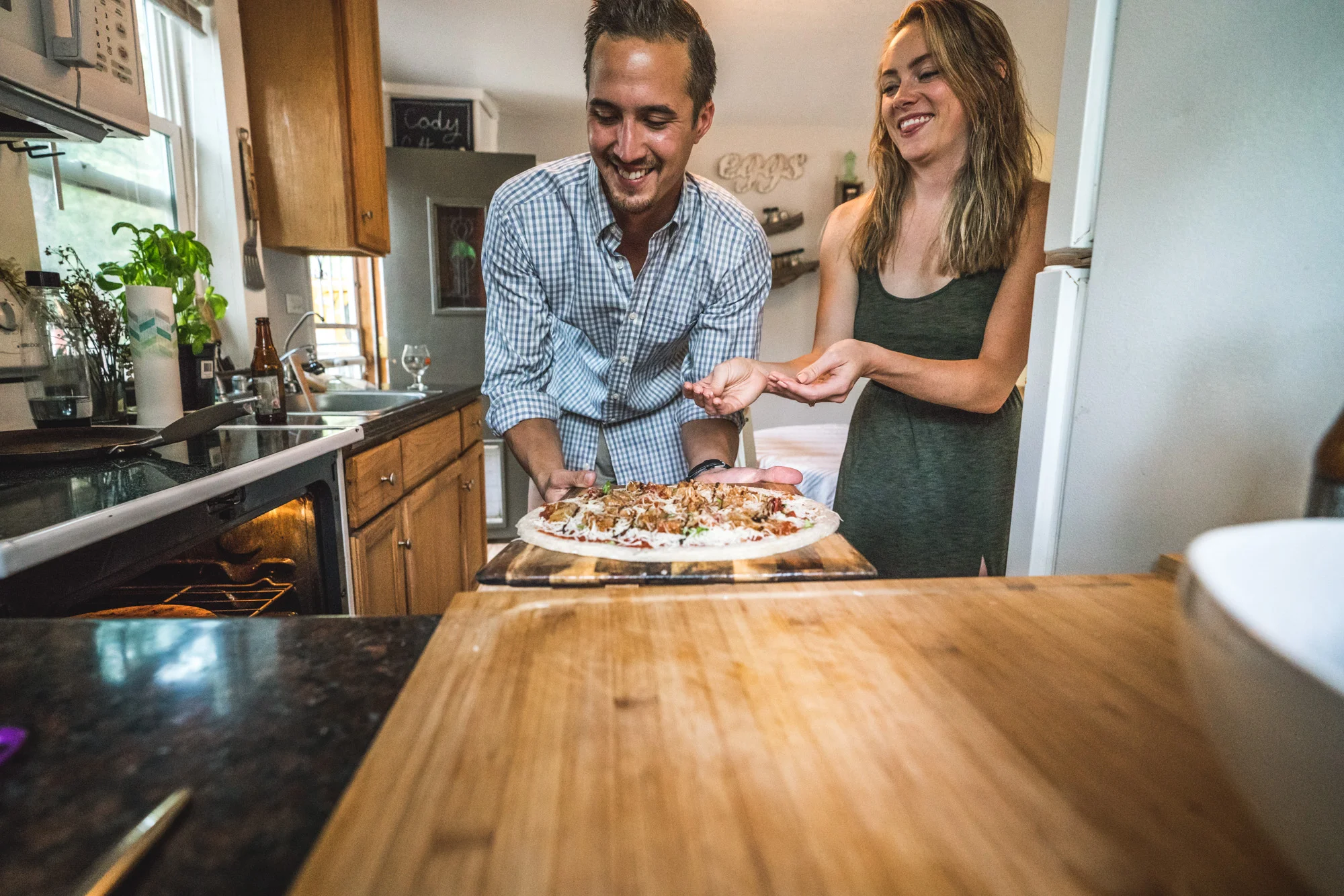 Engagement photo of a man and woman in their kitchen getting ready to put a pizza in the oven