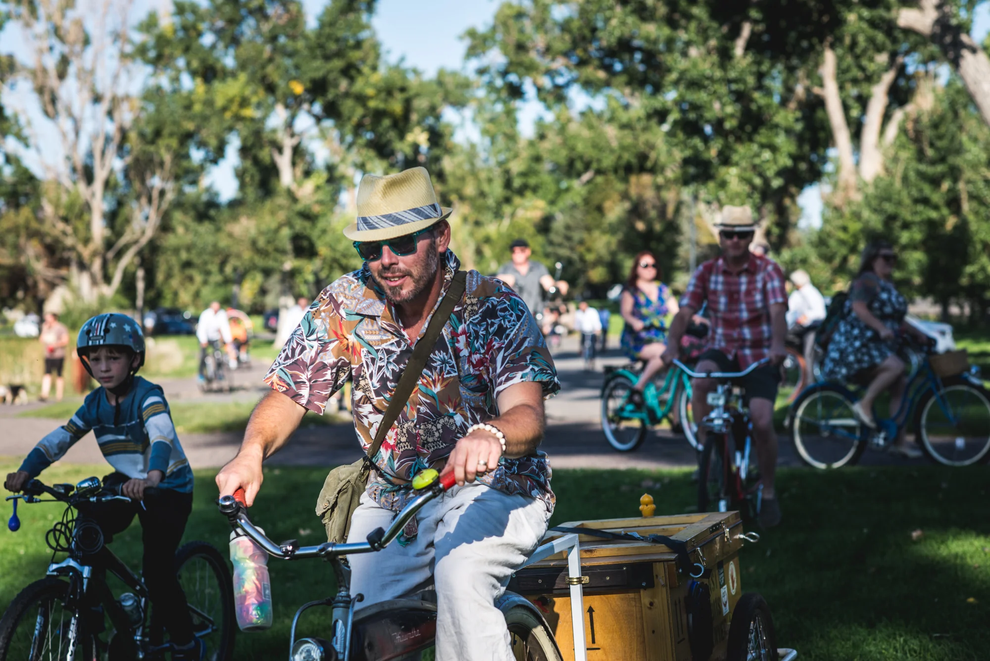Colorful photo of a man wearing a hat riding a bike with a lot of people on bikes surrounding him