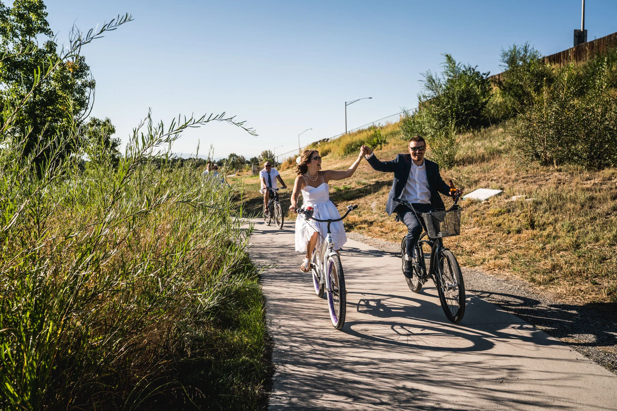 Bride and groom riding a bike around Berkeley Lake while holding hands