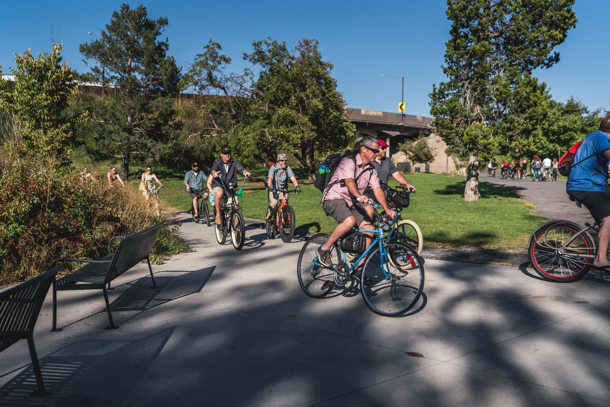 Group of people dressed for a wedding ride bikes around Berkeley Lake in Denver, Colorado