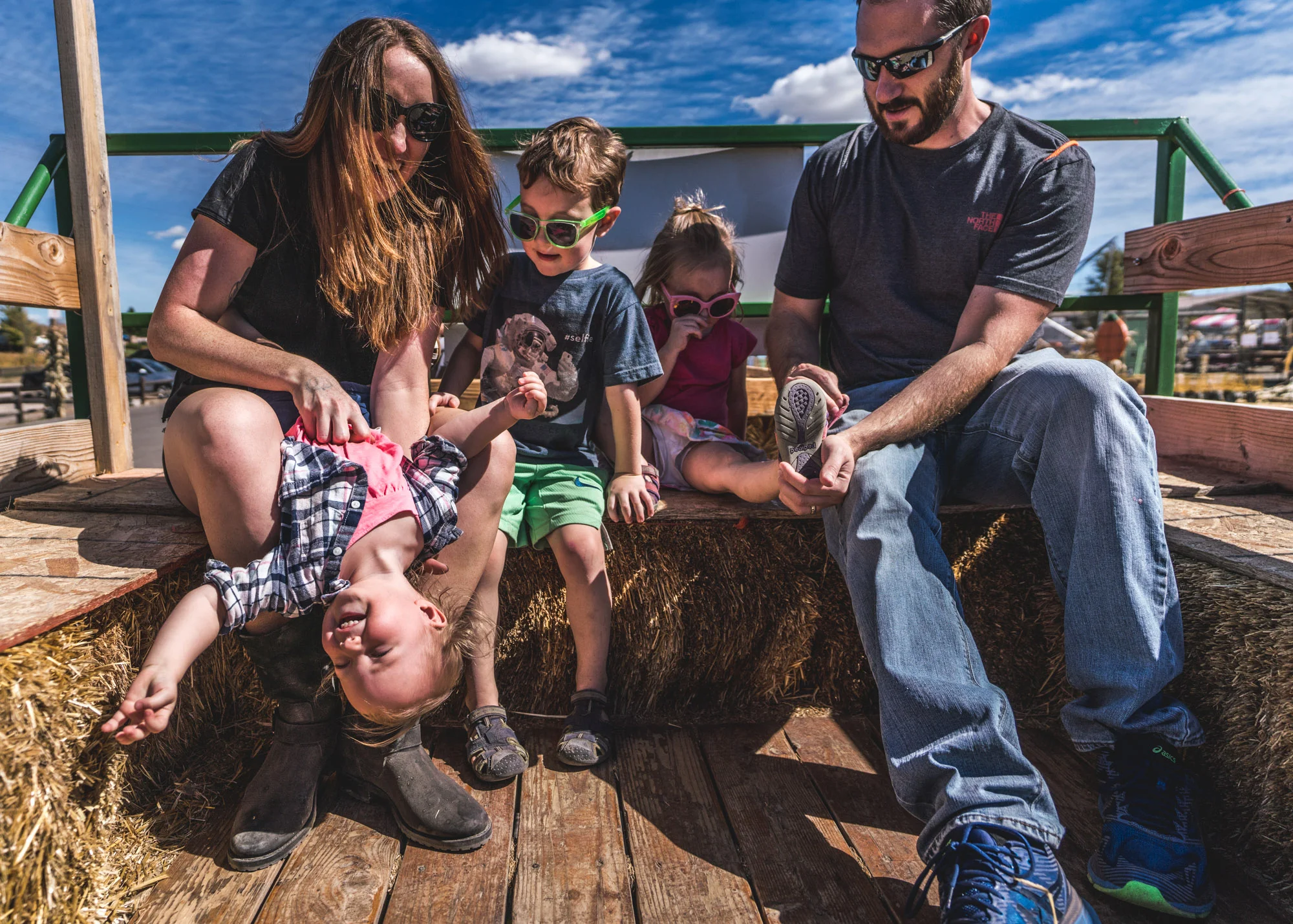 Parents and their three kids play around on the hay ride at a pumpkin patch in Parker, Colorado