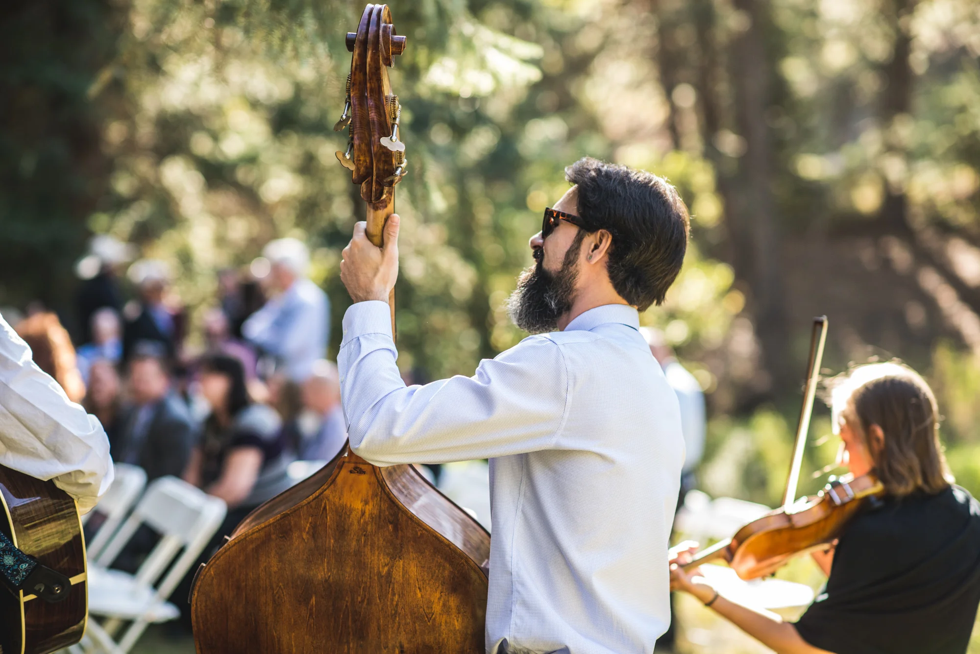 Man plays a cello and woman plays the violin at a wedding ceremony in the woods of Morrison, Colorado