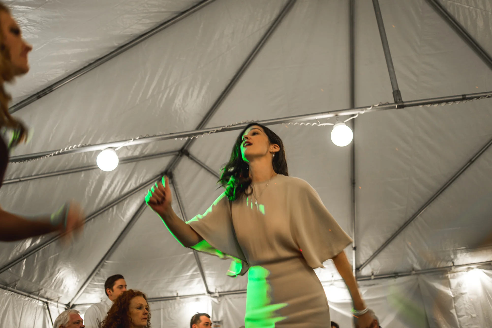 Woman dances in bright green lights at a wedding reception