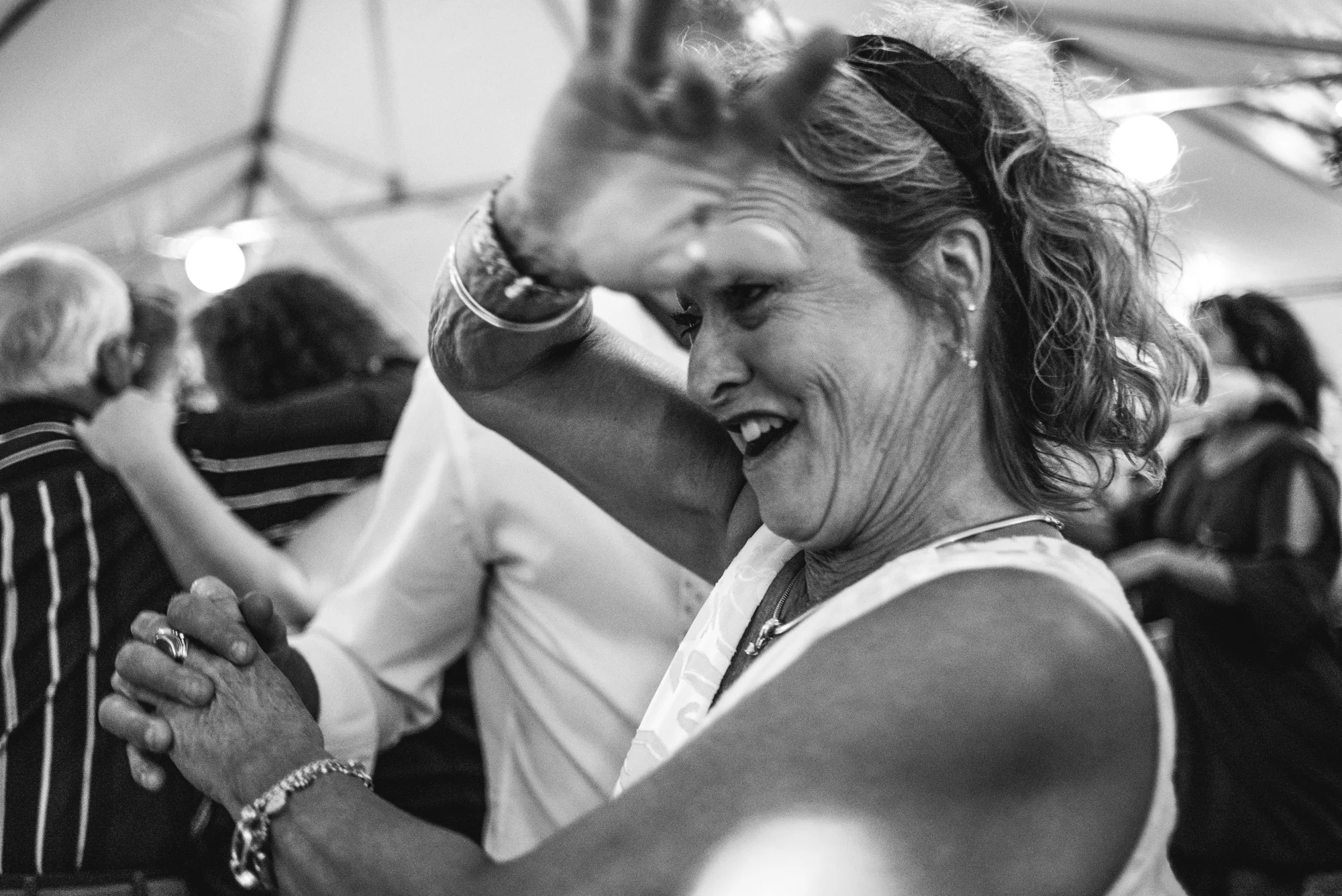 Black and white photo of a woman getting spun on the dance floor at a wedding reception