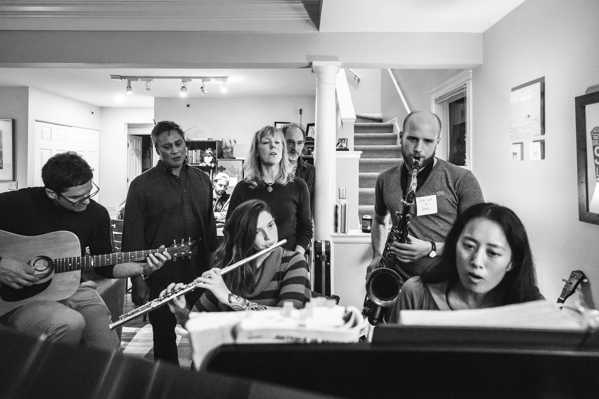 Group of people gathered around the piano, playing instruments and singing