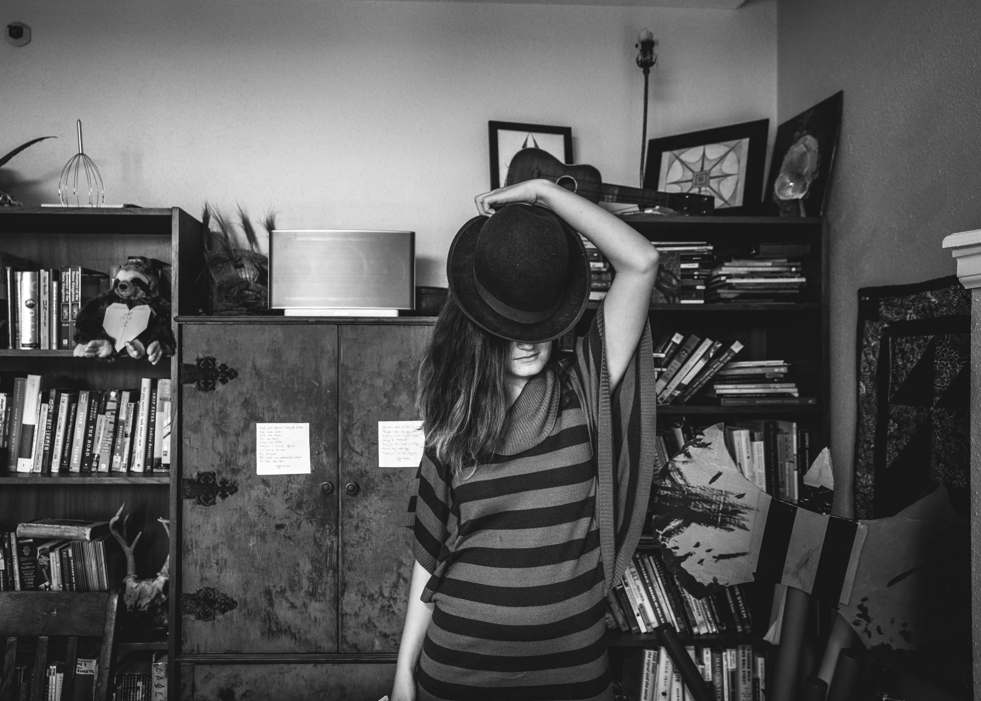 Young woman looks down as she tips her black hat forward