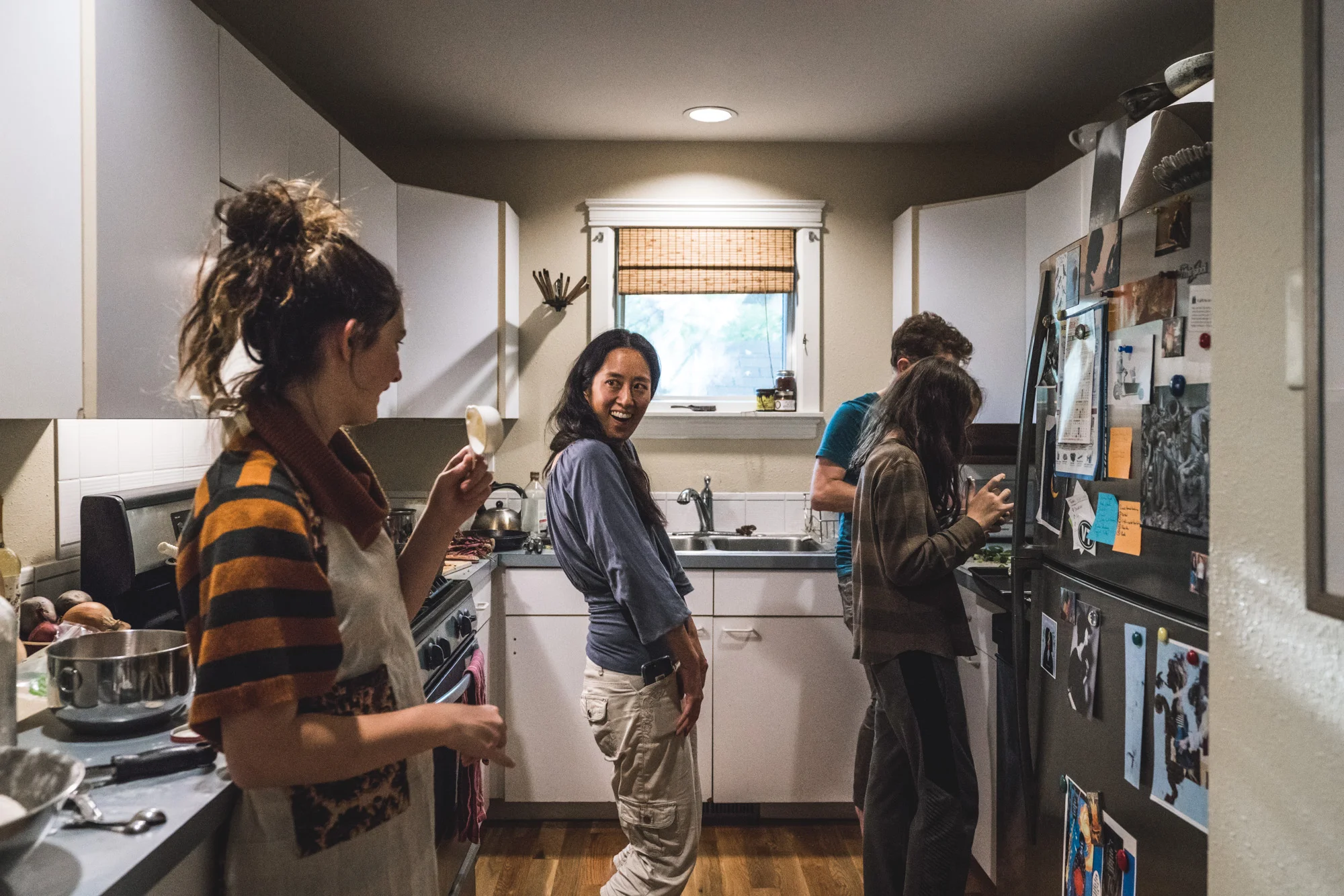 Woman in kitchen with family smiles wide