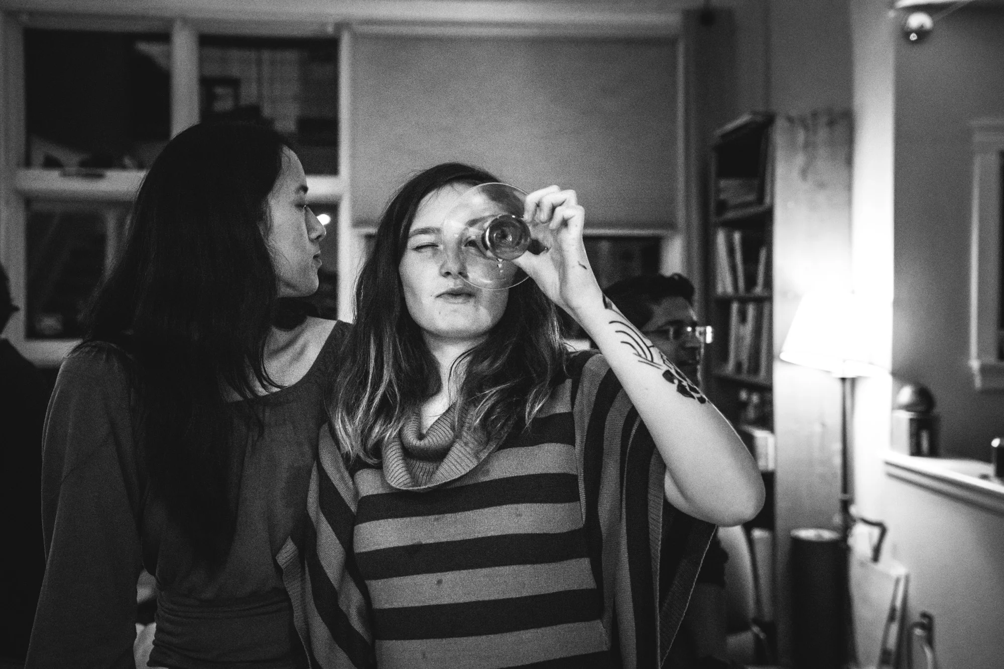Young woman puts martini glass to her eye and looks into the camera
