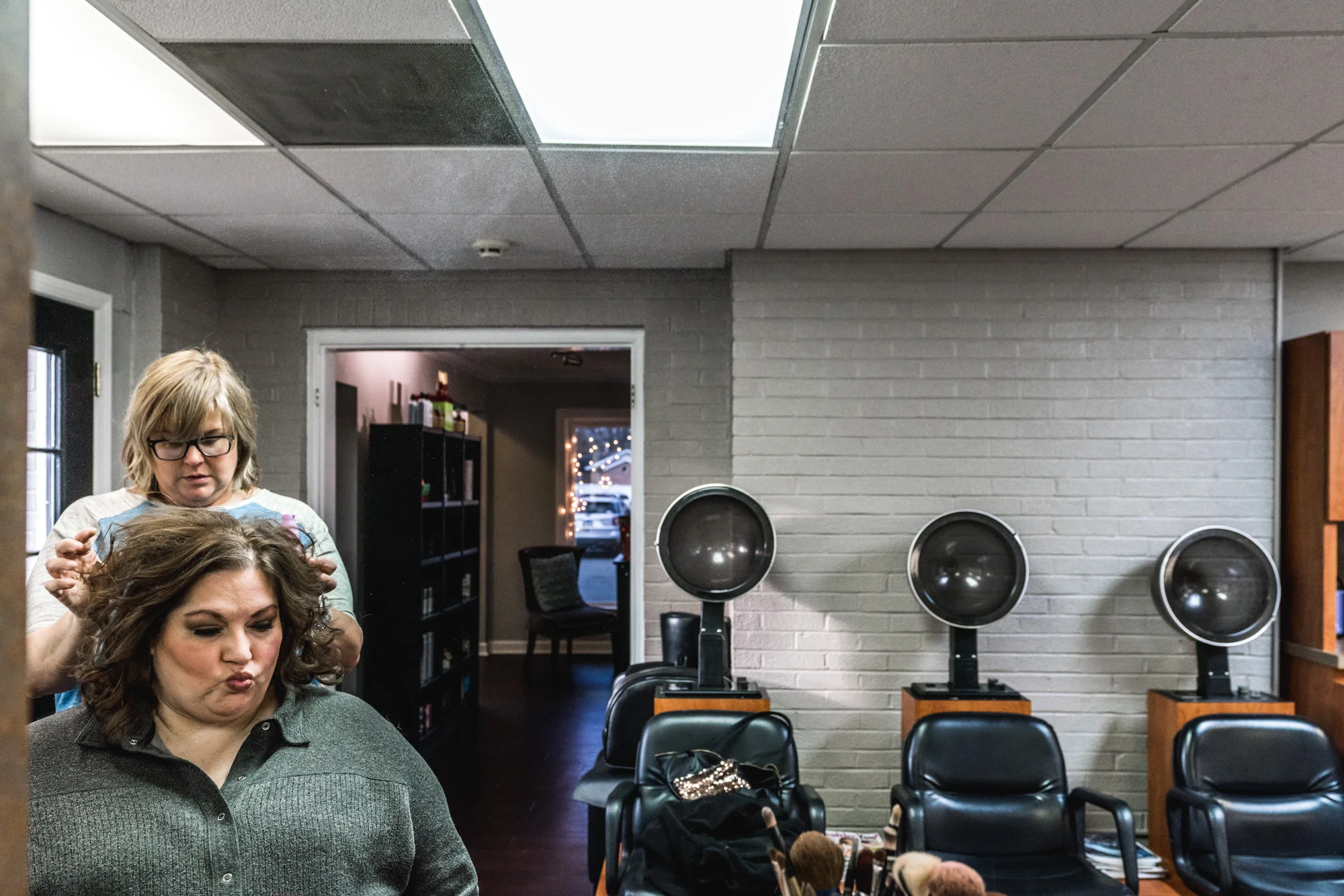 Bride sitting in a beauty parlor before her wedding getting her curls fluffed by the stylist
