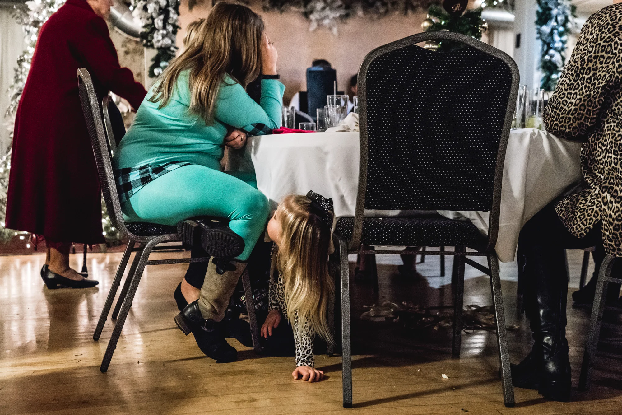 Kid at a wedding plays underneath a table