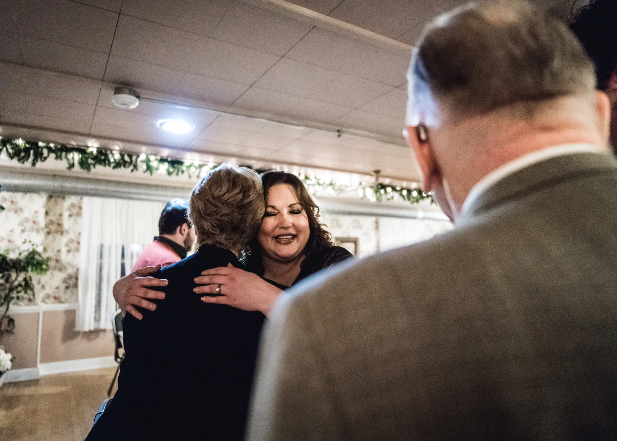 Bride smiles as she hugs a wedding guest