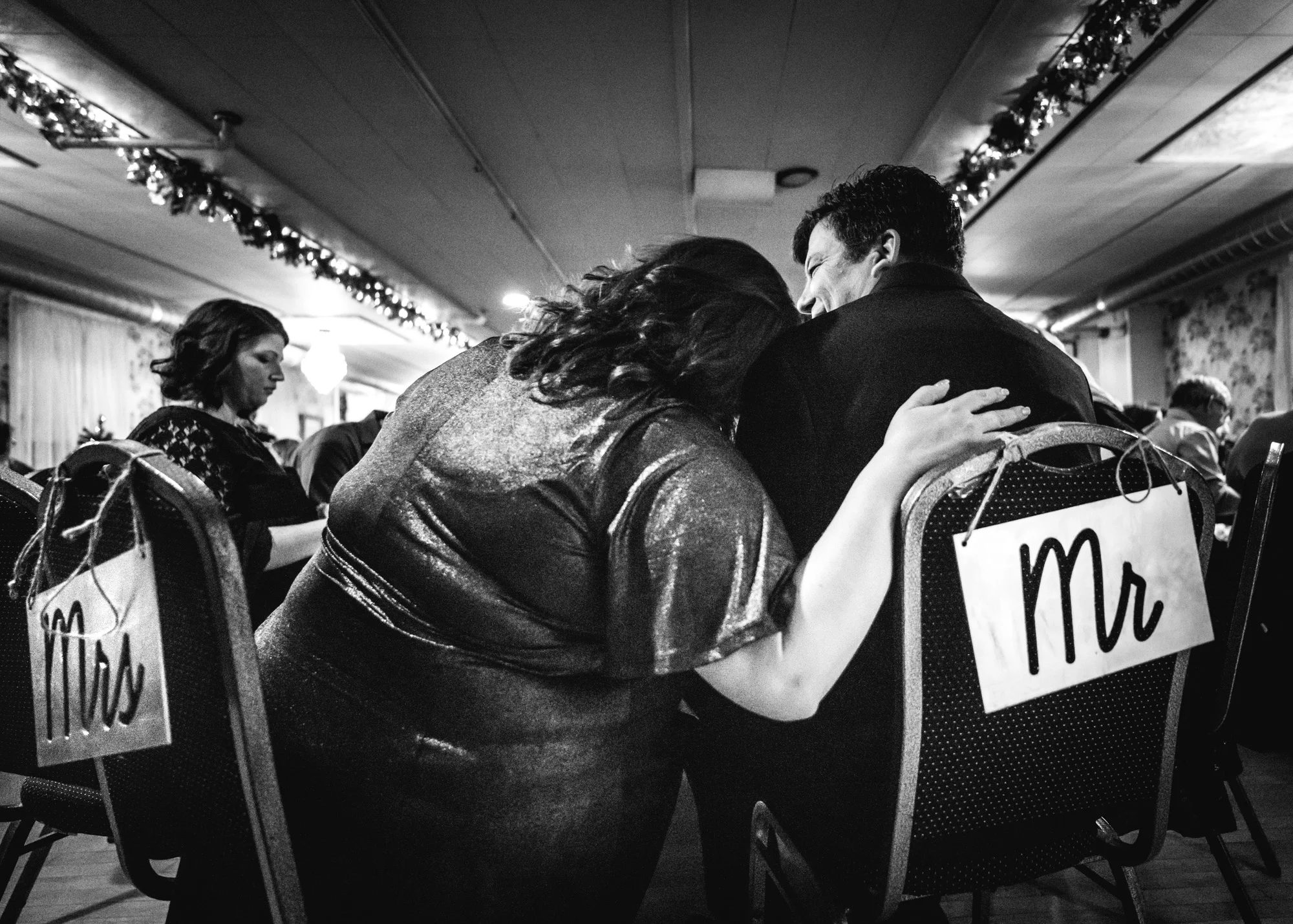 Newlyweds cuddle together at their wedding table
