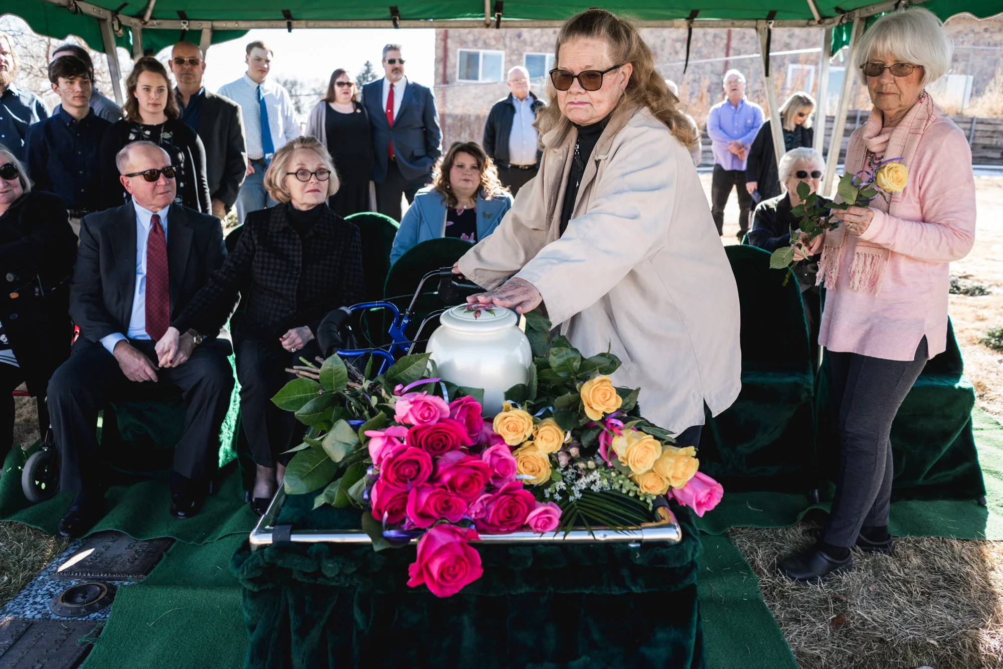 A woman places her hand lovingly atop the urn of a lost loved one at a memorial service at the cemetery in Greeley, Colorado