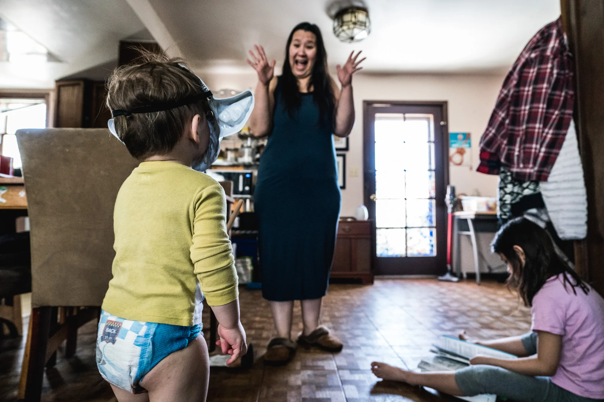 Little boy wearing a yoga mask turns to his mom who feigns surprise