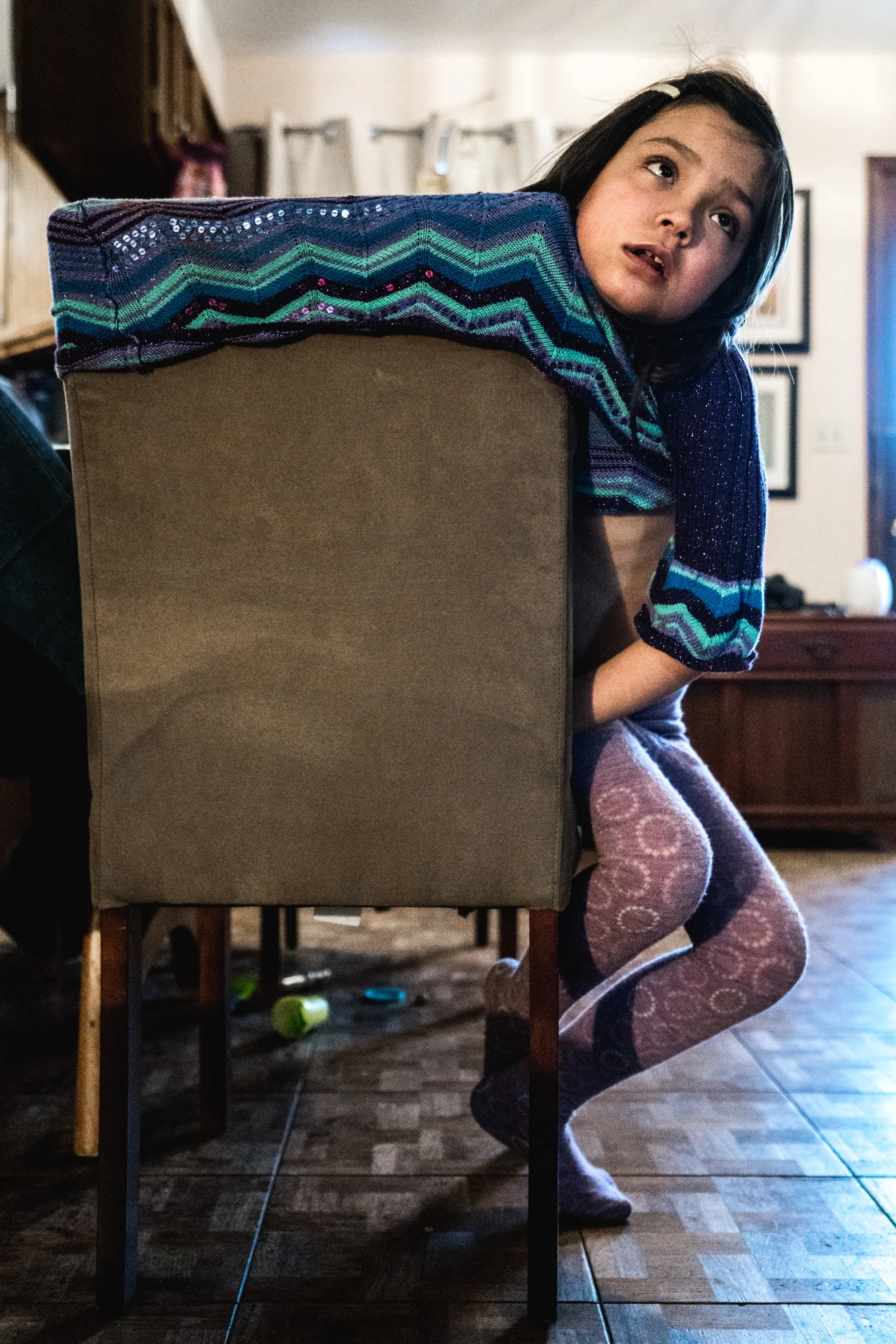 Little girl stretches her shirt over the back of her chair as she mindlessly watches television