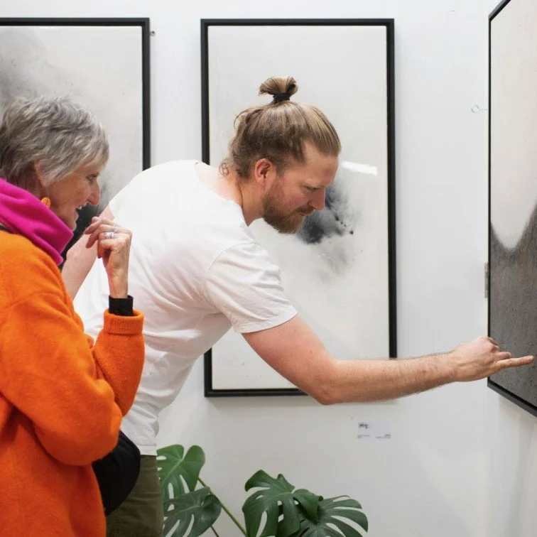 Artist showcasing his abstract painting to an art show visitor