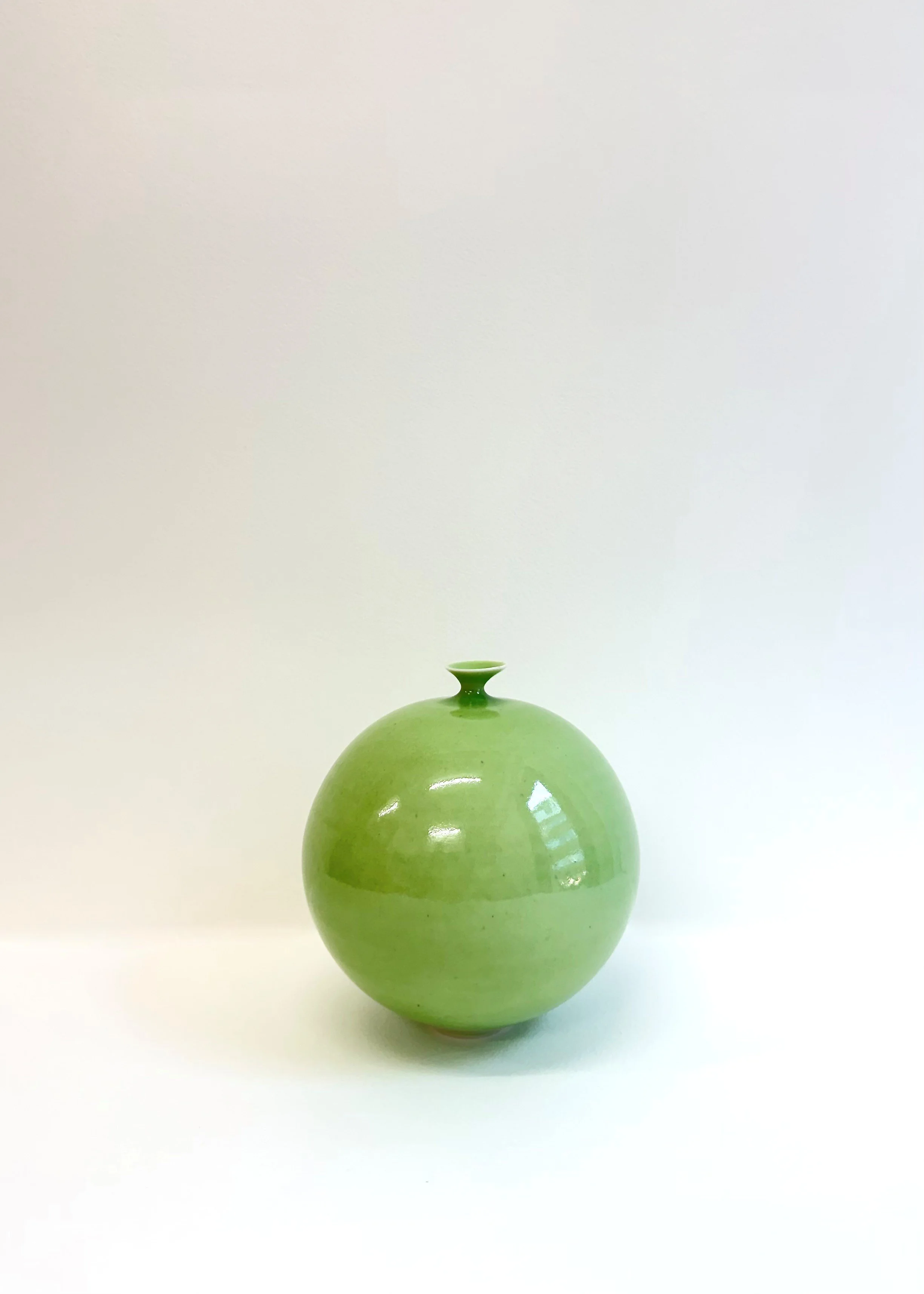 Red ceramic vase with a rounded body and a narrow neck against a white background.