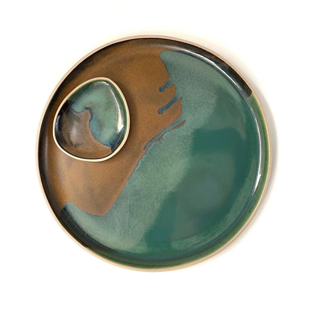 Three nested black bowls with white and blue glaze edges, viewed from above, on a dark surface.
