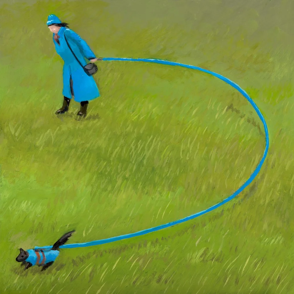Person in blue coat walking a small dog in a harness on a leash along a dirt path.