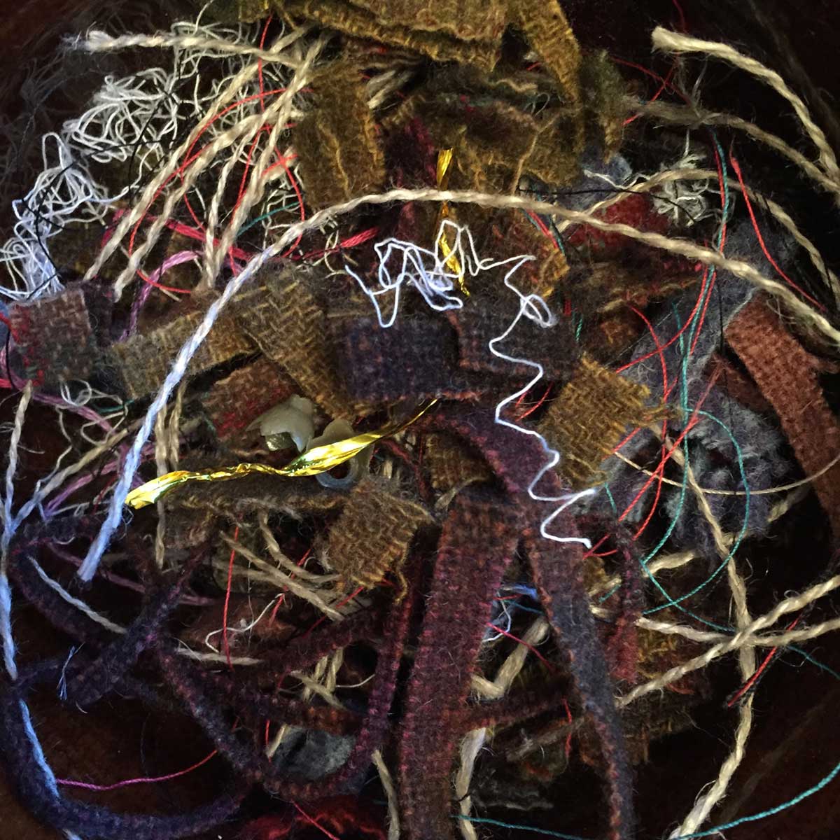 small bits of wool strips and threads in a bowl on my work table