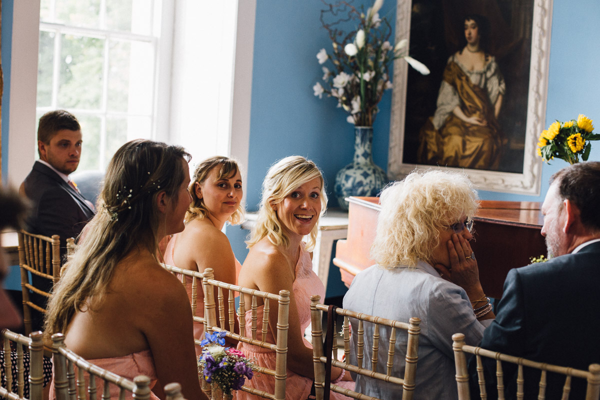 Bridesmaids laughing whilst Bride and Groom Sign Register