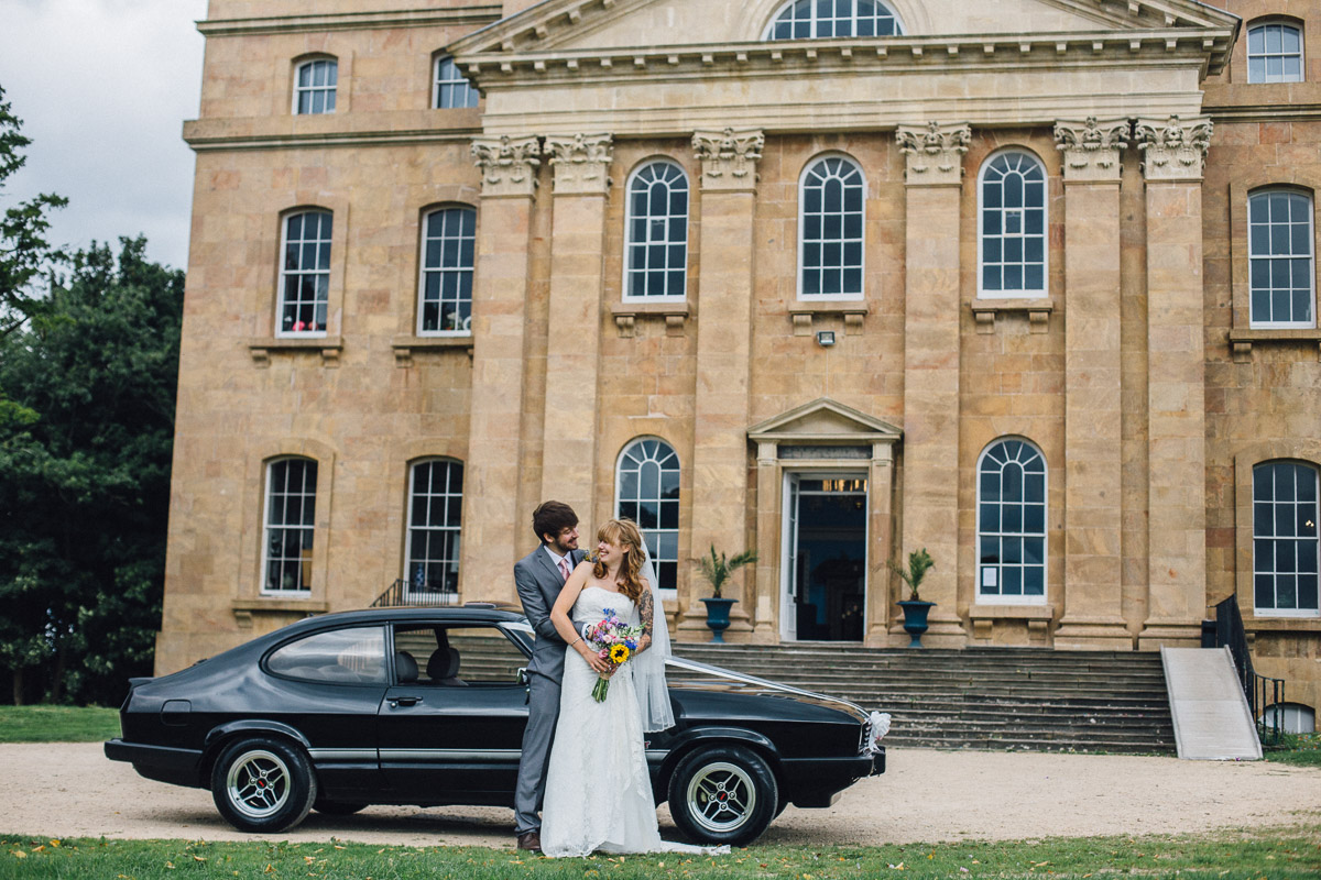 Bride and Groom Pose by Alternative Wedding Car outside Kings Weston House