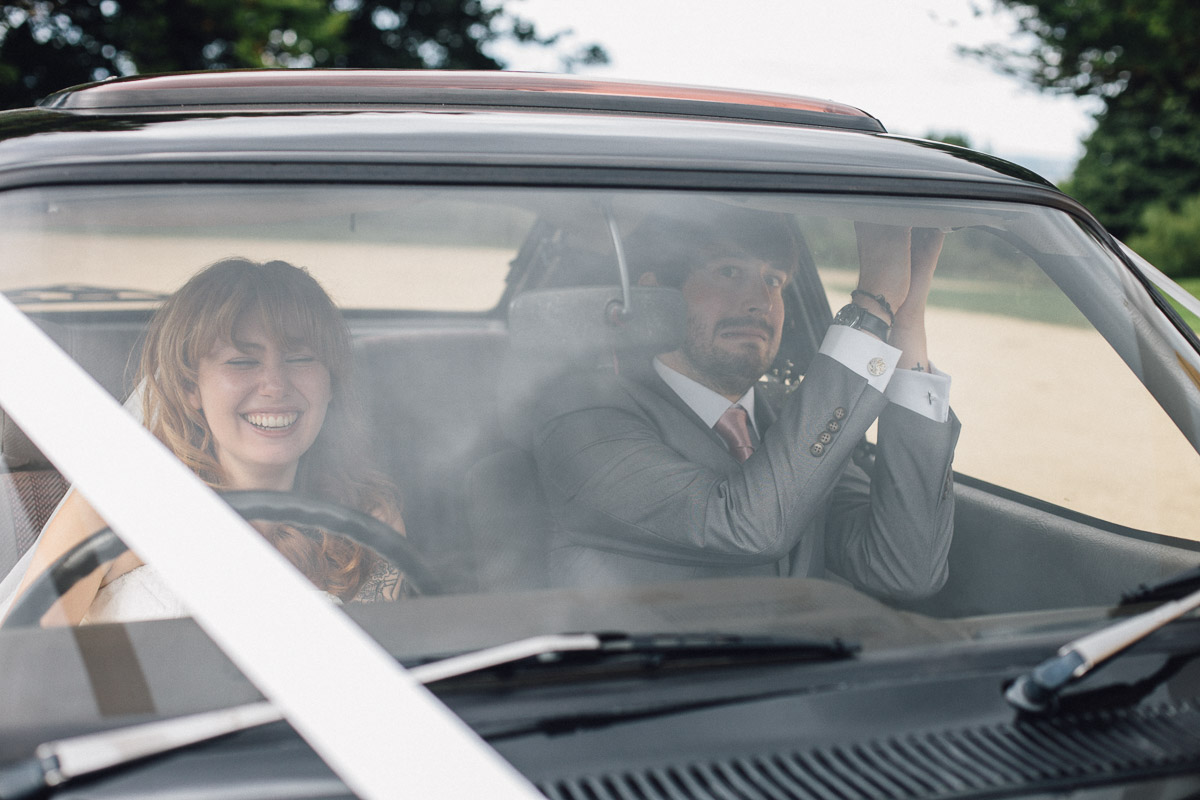 Bride Pretending to drive wedding car groom looks scared