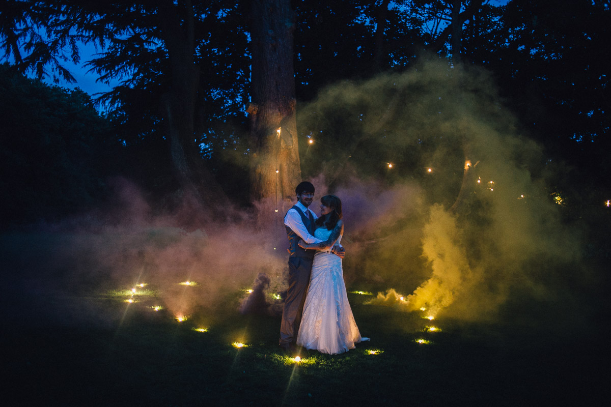 Alternative Couple portrait at night in Festoon lights and Yellow and Purple Smoke Bomb