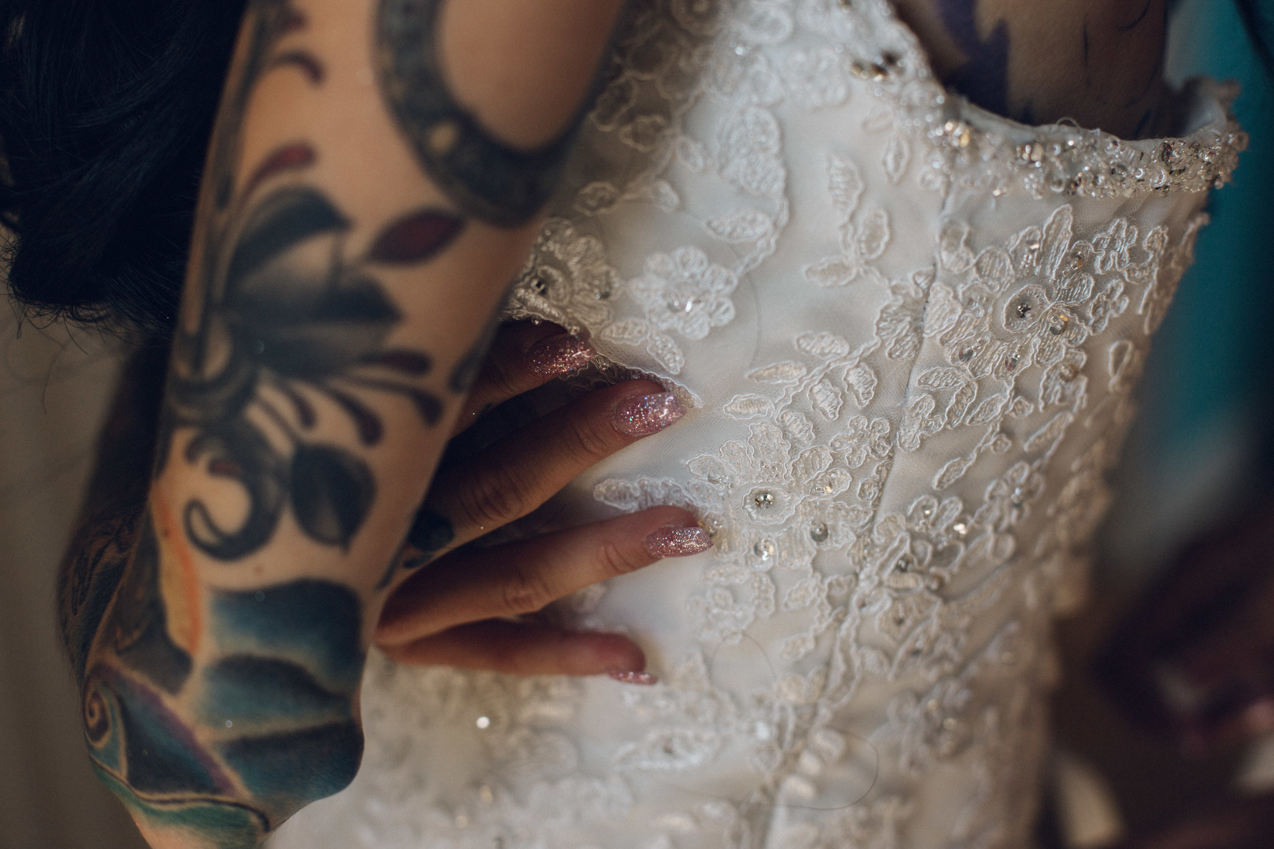 Heavily tattooed bride putting dress on 