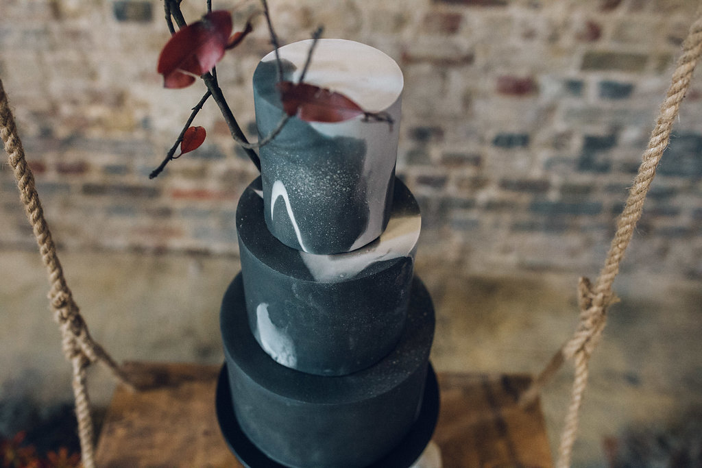 Black wedding cake on a floral cake arch swing - Asylum Chapel Wedding, London 