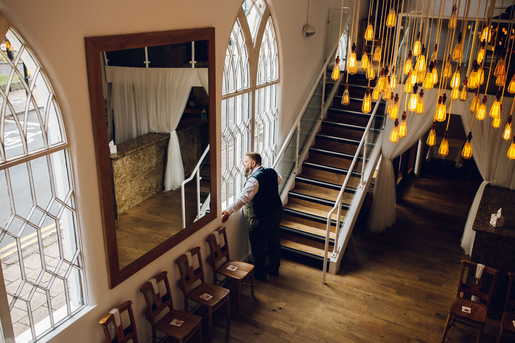 Groom looks out window before ceremony 0 Intimate Essex wedding Old Parish Rooms