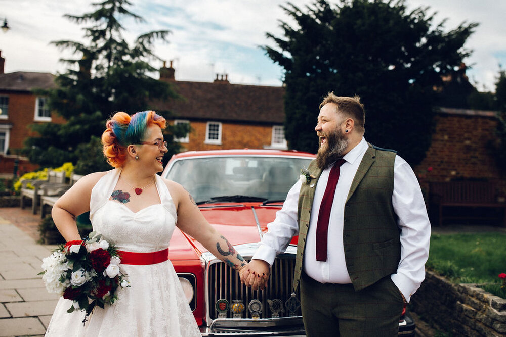Alternative colourful couple in front of red car - Intimate Essex wedding Old Parish Rooms