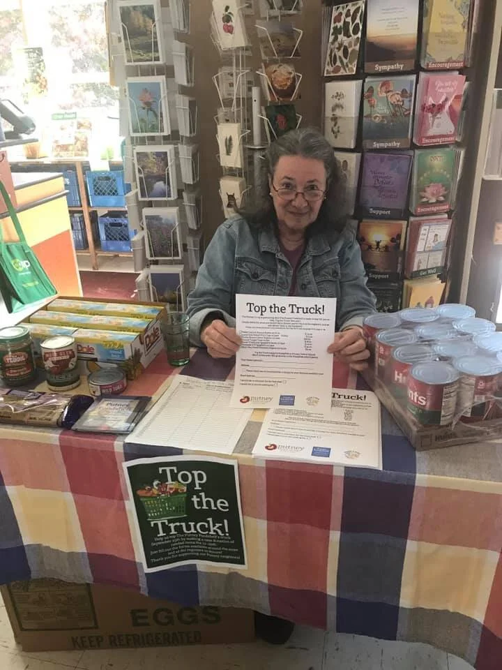 Board President, Nancy Olson mans the table at the Putney Co-op where folks could order cases of food at bulk rates for the Foodshelf.