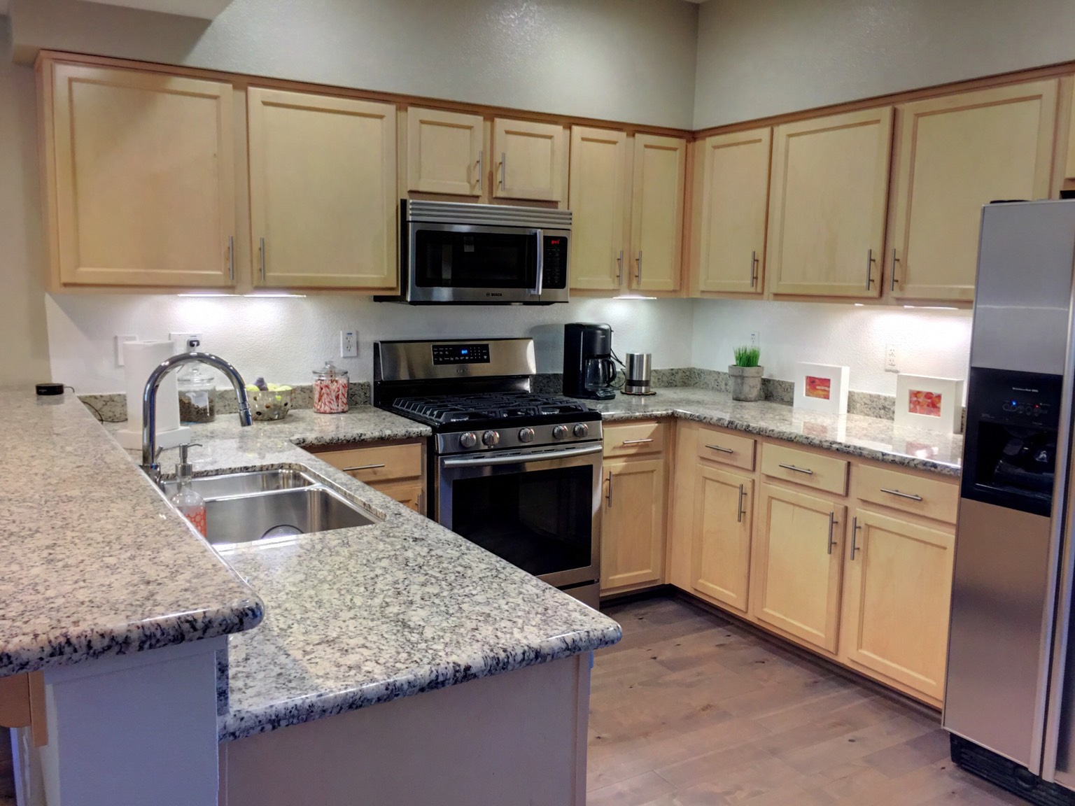 Gas range, stainless appliances and granite countertops in kitchen.