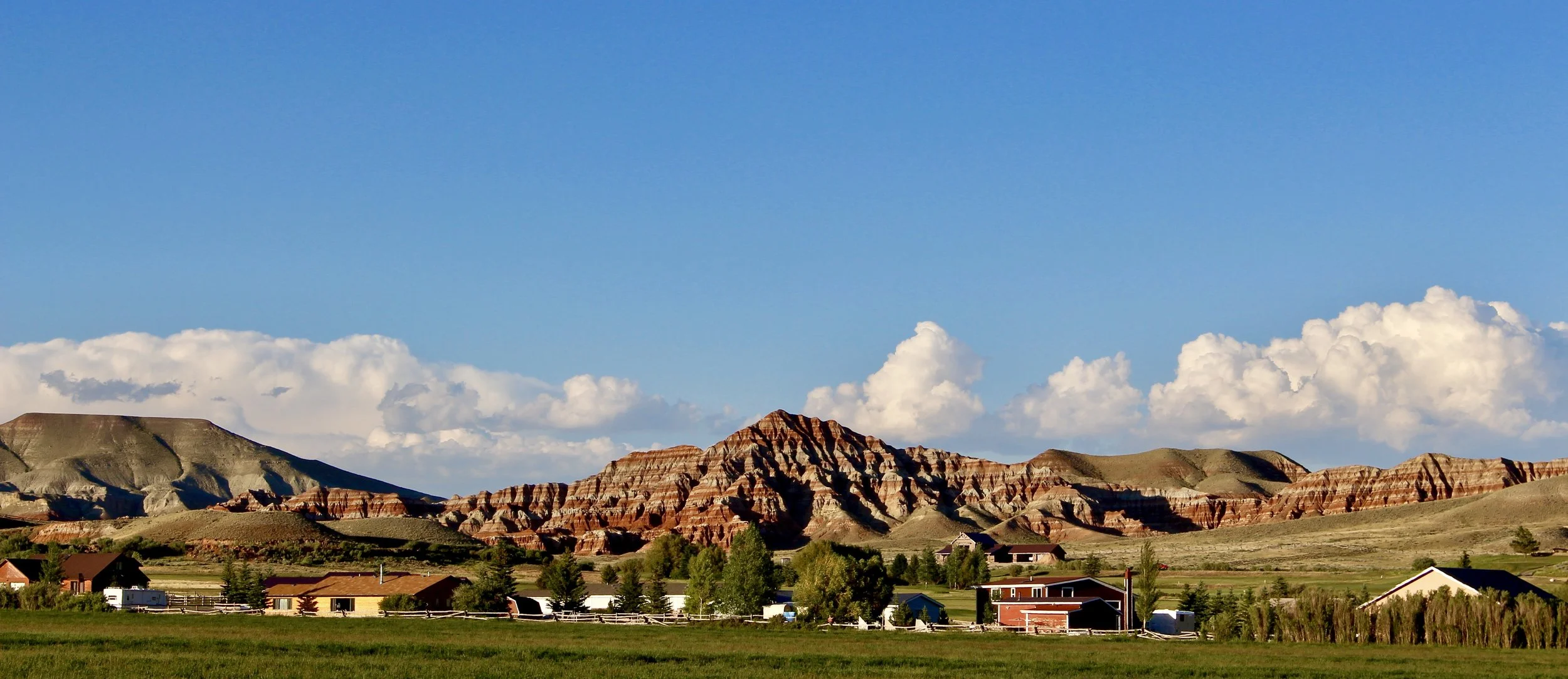 Ranches are flanked by mountains as the roads lead into town
