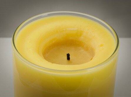 Burning Candle On Grass Plate With Melting Wax Stock Photo