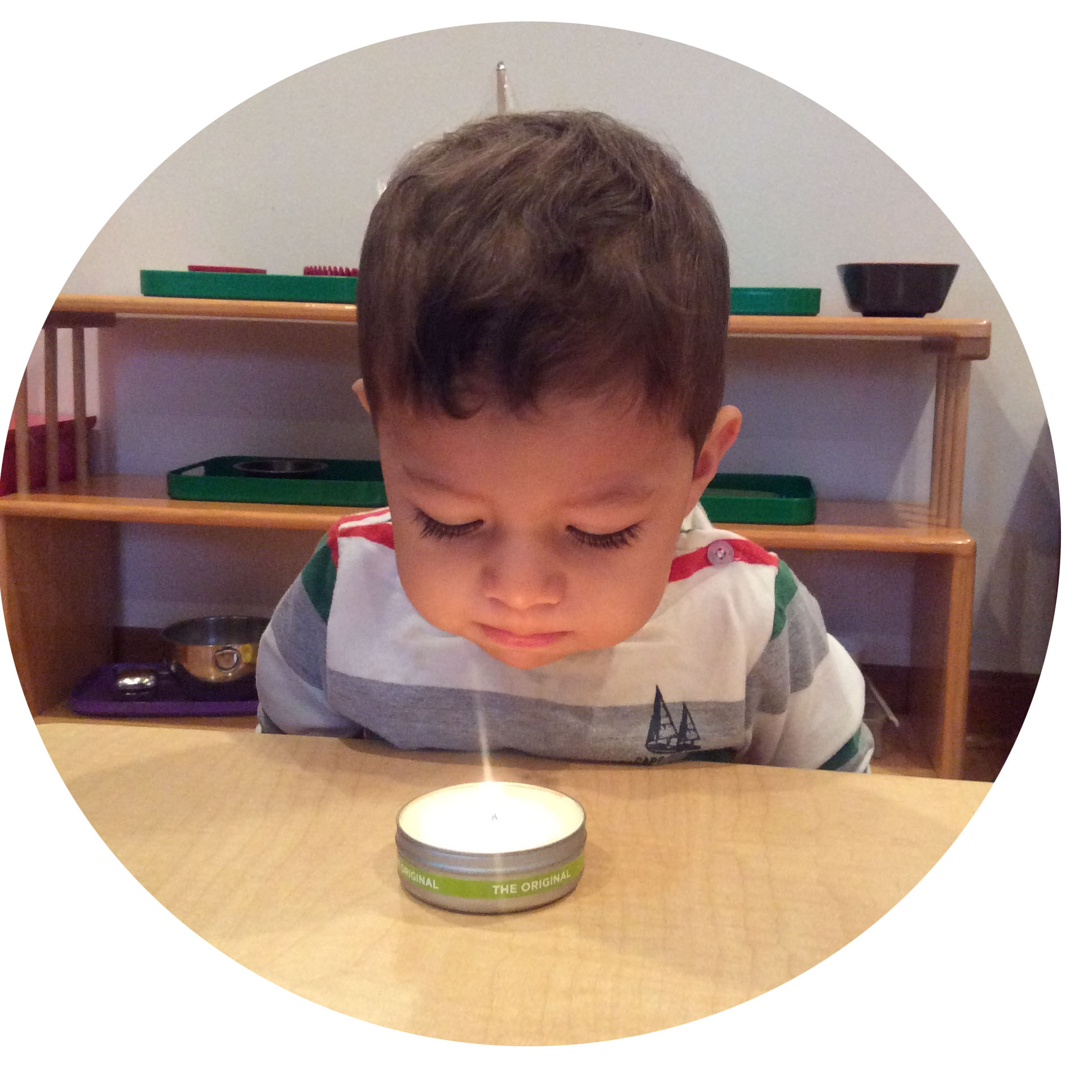 A toddler learns how to use breath to gently blow out the candle.