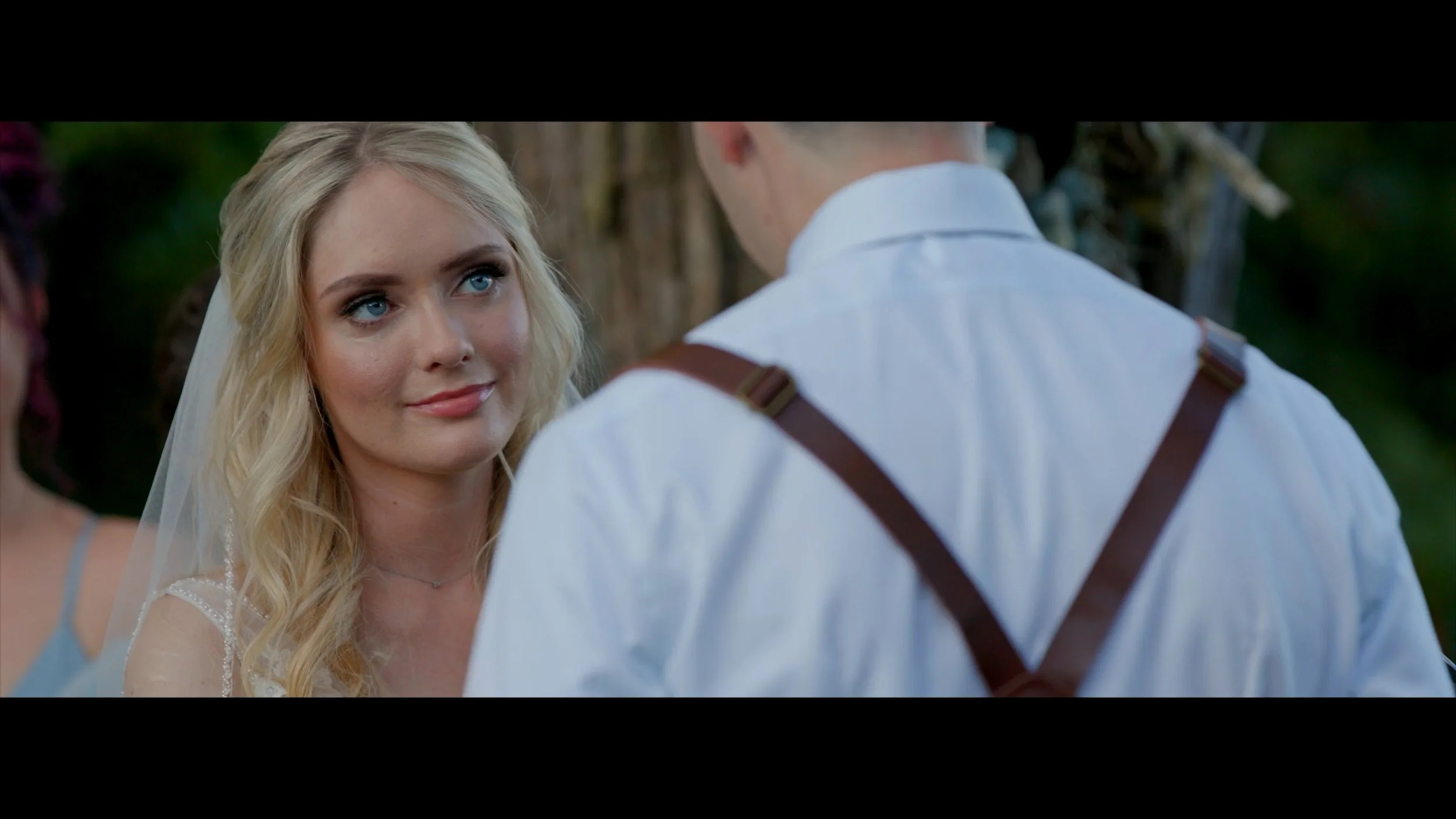 bride listening to her husbands vows at knotted roots on the lake