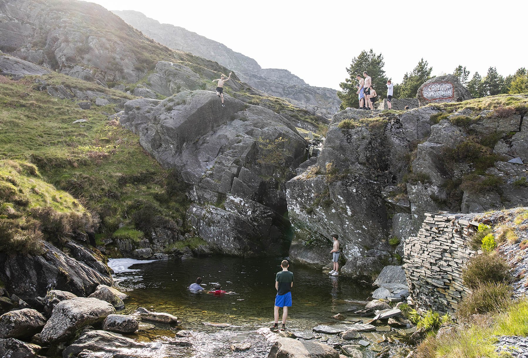  Boys jumping in to a pool in the slate landscape in Snowdonia above Blaenau Ffestiniog.  